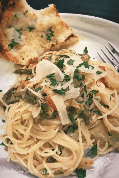 Pasta with shrimp, asparagus, artichoke and tomato topped with shaved parmesan and chopped parsley