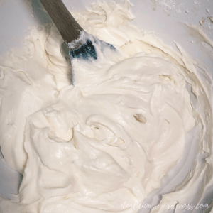 Cream cheese filling inside of a deep white bowl with a spatula inserted