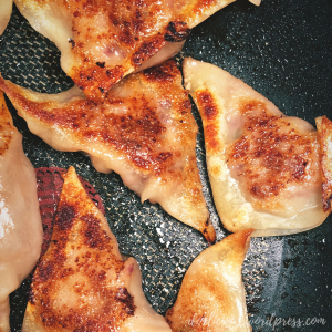 Browned potstickers inside a lightly oiled pan