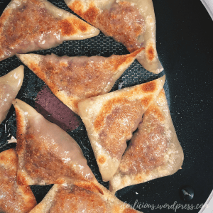 Potstickers inside of a lightly oiled pan that have been lightly browned