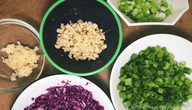 Bowls of minced ginger, pressed garlic, minced cabbage and sliced scallions