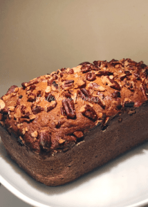 image looking at the banana bread at an angle on a white plate and removed from the loaf pan
