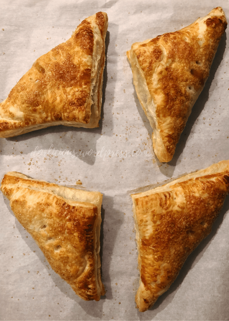 overhead photo of apple turnovers on a baking sheet lined with parchment paper