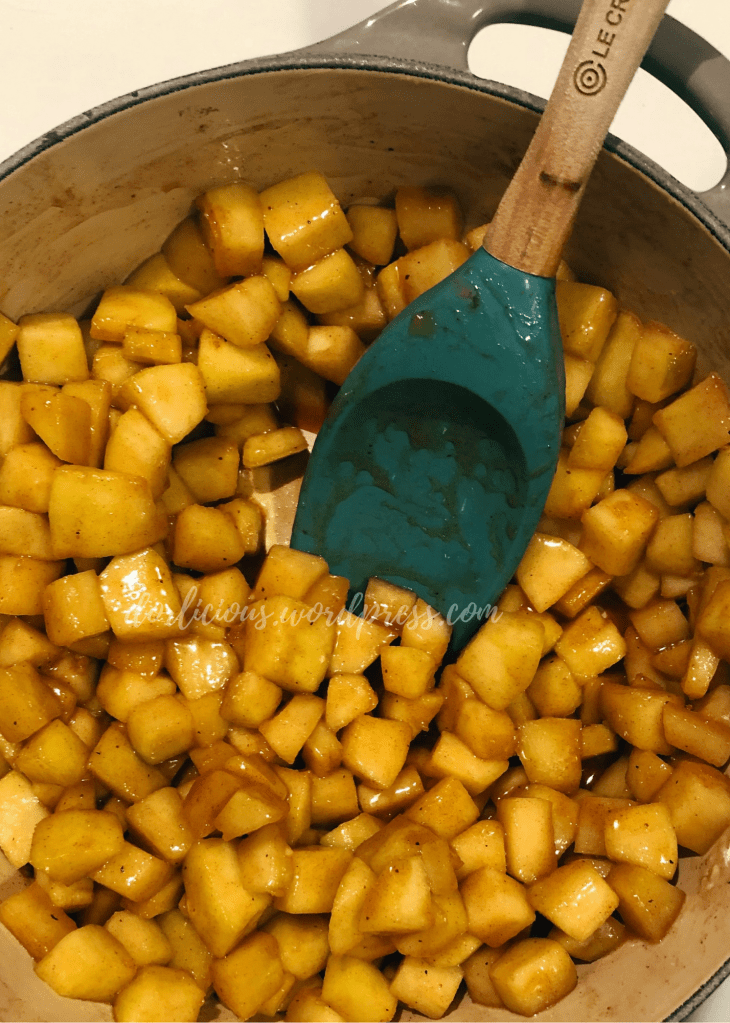 apples in a pot with a spoon coated in sugar syrup